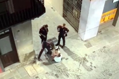 Captura del vídeo del moment en què l'agent dels mossos venta una bufetada a l'home assegut al mig del carrer a Olot.