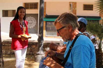 Una voluntària de la Creu Roja oferint gorres als sense sostres en plena onada de calor.