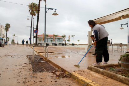 Veïns d'Alcanar retiren aigua i fang acumulat al Passeig Marítim.