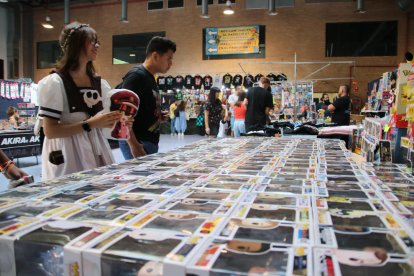 Dues persones mirant una de les paradetes de la fira Tarraco Manga de Tarragona.