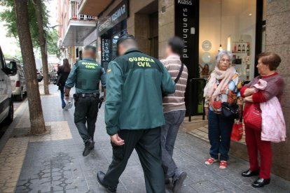 Dos policies de la Guàrdia Civil sortint amb un detingut en un dels registres fets a Tarragonal'operatiu policial conjunt amb els Mossos d'Esquadra.