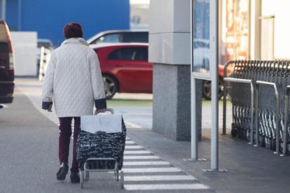 Una mujer sale de un supermercado con la carretilla de comprar.