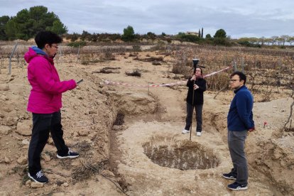 Trabajos de topografía en el yacimiento, con el Mas Cap de Ferro al fondo.