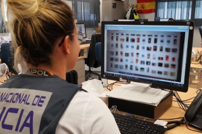 Una investigadora de la Policía Nacional analizando los archivos localizados en el registro en casa de un menor de edad detenido por producir y distribuir pornografía infantil con inteligencia artificial.