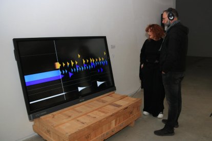 Dos espectadores escoltan la obra 'Contorns', en el marco de la exposición 'FORMS - música visual generativa' en Lo Pati -  Centre d'Art de les Terres de l'Ebre.