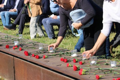 Familiares de víctimas de tráfico ofreciendo flores y velas en el memorial situado en el paseo marítimo de la Nova Icària de Barcelona.