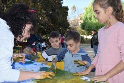 Una de les dinamitzadores, l'Elisa, pintant el mural amb alguns dels nens participants.