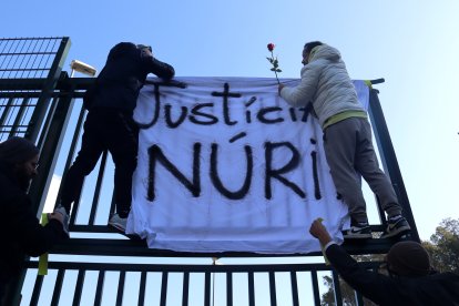 Dos treballadors de Mas d’Enric, aquest divendres, penjant una pancarta i una rosa a les portes del centre penitenciari.