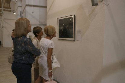 Tres dones observen una fotografia inclosa a la mostra 'Horta Picasso Mont-roig Miró' a l'església vella de Mont-roig del Camp.