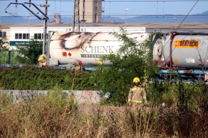 Els Bombers al costat del vagó del tren de mercaderies que s'ha incendiat a Girona.