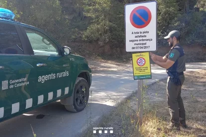 Un Agent Rural col·loca un cartell de prohibició de circulació per perill d'incendi forestal