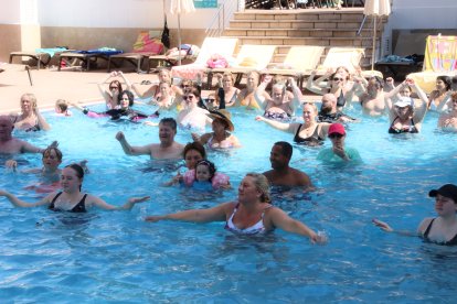 Un grup de persones fan una classe dirigida a una de les piscines de l'hotel Golden Port de Salou.