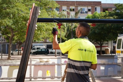 Un operari de les Brigades Municipals treballant en el manteniment del mobiliari urbà.