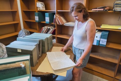 La cap de la biblioteca, Montserrat de Anciola, consultant documentació de l’arxiu històric de l’entitat