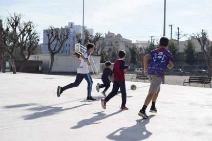 Diversos nens jugant en un pati d'una escola oberta els dissabtes.