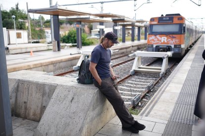 Un usuari capcot espera el tren a l'estació de Sant Vicenç de Calders