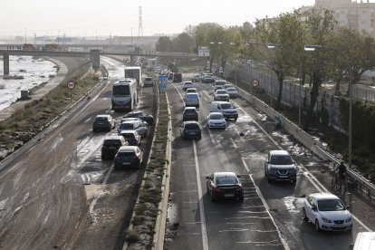 Diversos cotxes circulen entre els vehicles afectats per la dana a la V30 a l'altura de La Torre aquest dijous a València.