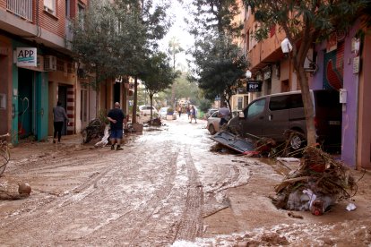 Un dels carrers de Picanya ple de fang i de veïns netejant