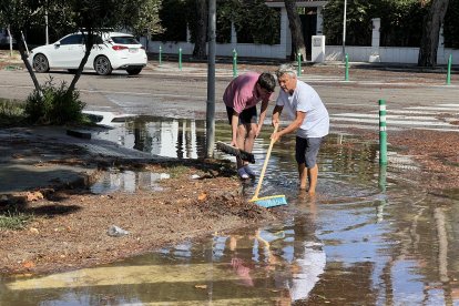 Dos veïns treuen aigua del carrer Josep Vicenç Foix de Sitges, anegat per la tempesta.