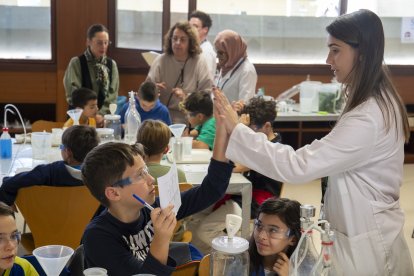 Uno de los alumnos chocando las manos con una de las estudiantes de la URV encargada de impartir los talleres.