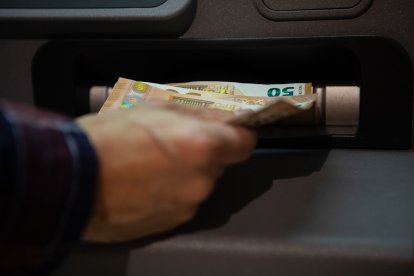 Una persona que retira diners d'un caixer automàtic