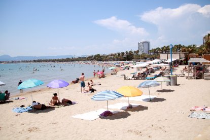 Turistes i banyistes prenent sol i banyant-se a la platja de Salou