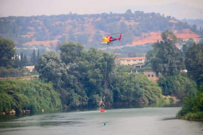 Un helicòpter d'extinció agafa aigua al riu Ebre, davant de Xerta.