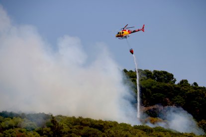 Un helicòpter descarrega aigua en un incendi forestal a Alforja.