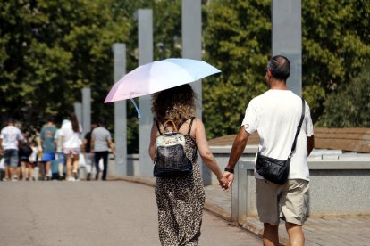 Una mujer anda|camina con un paraguas por|para la pasarela del Liceo Escolar, en Lleida.