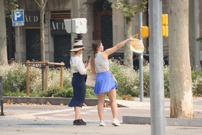 Dues turistes amb barrets durant el pic de l'onada de calor aquest diumenge a Barcelona.