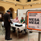 Un cartel indicativo y de un elector votando en uno de los colegios electorales de la ciudad de Tarragona.