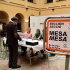 Un cartell indicatiu i d'un elector votant en un dels col·legis electorals de la ciutat de Tarragona.