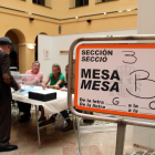 Un cartell indicatiu i d'un elector votant en un dels col·legis electorals de la ciutat de Tarragona.