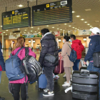 Un grup de passatgers miren el tauler de sortides de l'aeroport de Reus.