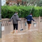 Un home i una dona caminant amb cubells per un dels carrers inundats de la urbanització La Móra de Tarragona