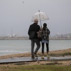 Dues persones es protegeixen de la pluja amb un paraigües a Cambrils.