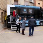 Uns quants veïns entrant i sortint de la Banca Mòbil de CaixaBank a la Pobla de Massaluca.