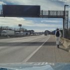 El jove circulant amb patinet pel voral de l'AP-7, al Gironès, amb el cotxe dels Mossos al darrere, custodiant-lo.