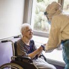 Una anciana amb una infermera amb l'EPI durant la pandèmia covid-19.