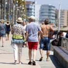 Plano general de varios turistas paseando por el paseo marítimo de la playa de la Pineda, en Vila-seca.