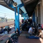 Viatgers asseguts a l'andana de l'estació de l'Aldea després de l'apagada elèctrica i l'aturada dels seus trens aquest dilluns al migdia