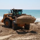 Una de les màquines traslladant sorra a la platja de Calafell.