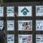 Una dona mirant els anuncis d’habitatges exposats en una immobiliària.