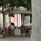 Un grup de noies en una terrassa a l'ombra i amb ventalls durant el pic de l'onada de calor a Barcelona.