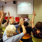 Un grupo de abuelos levantan las manos siguiendo las instrucciones de una terapeuta en un taller de psicomotricidad a la asociación AFAB para enfermos de Alzheimer.