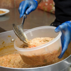 Els cuiners omplen les carmanyoles de les famílies per emportar-se el dinar a casa.