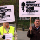 Dos membres d'Adicae amb pancartes aquest dimecres a la Ciutat de la Justícia de l'Hospitalet.