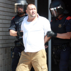 Uno de los detenidos escoltados por dos Mossos D'Esquadra en la salida de uno de los domicilios registrados del barrio del Templo de Tortosa.
