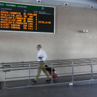 Un home amb una maleta passa per davant del panell que anuncia les sortides a l'estació de Tarragona el 10 de juny de 2016