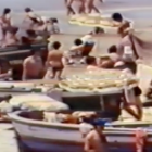Una imatge del vídeo, on es poden veure persones a la platja amb les barques sobre l'arena.